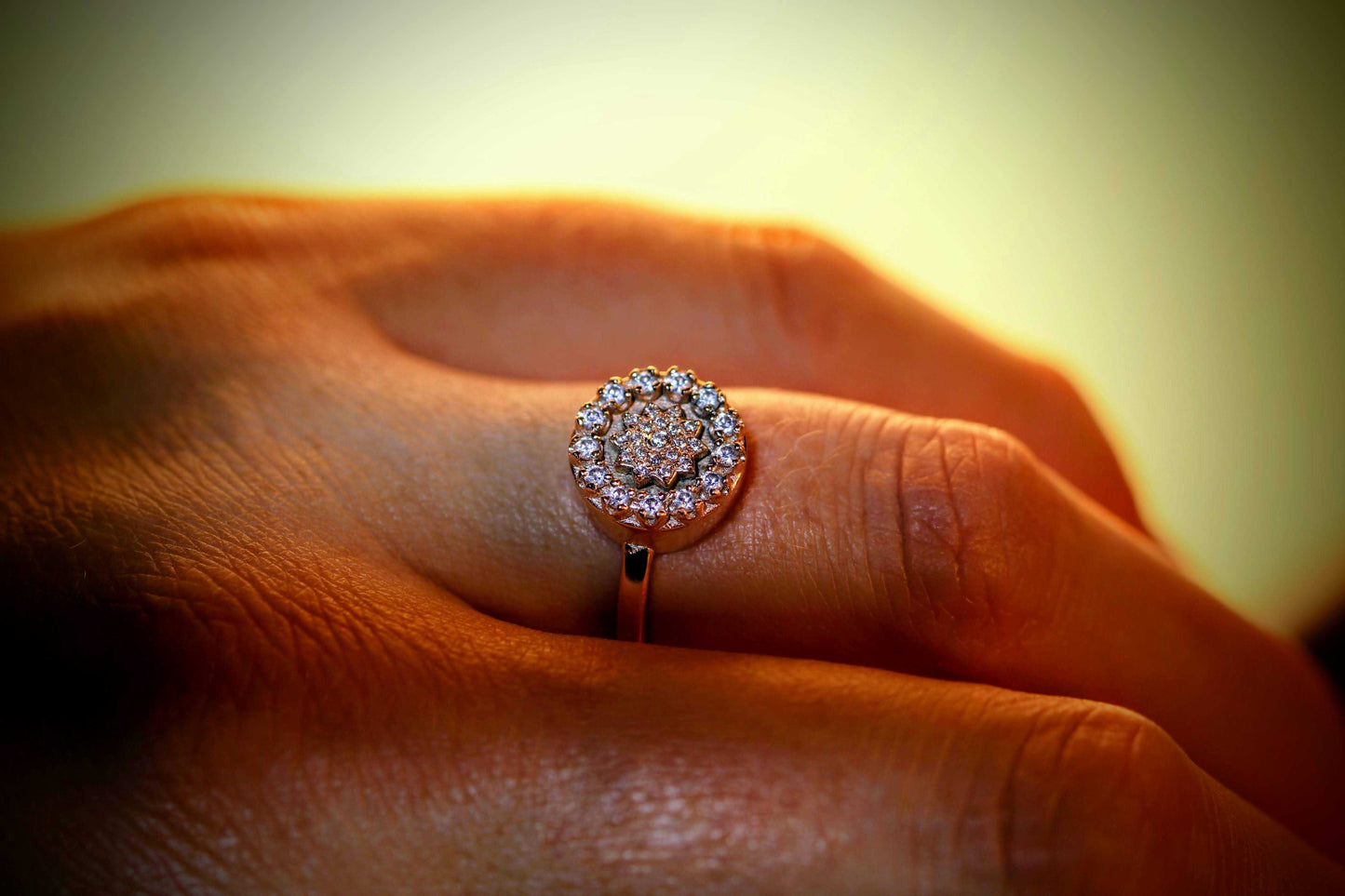 Gatsby van Olivia Peeters Master Goldsmith: luxe gouden ring met een cirkelvormig design, bezet met schitterende diamanten in een stervormig patroon en gedragen aan een hand, gepresenteerd in warm licht voor een elegante uitstraling.