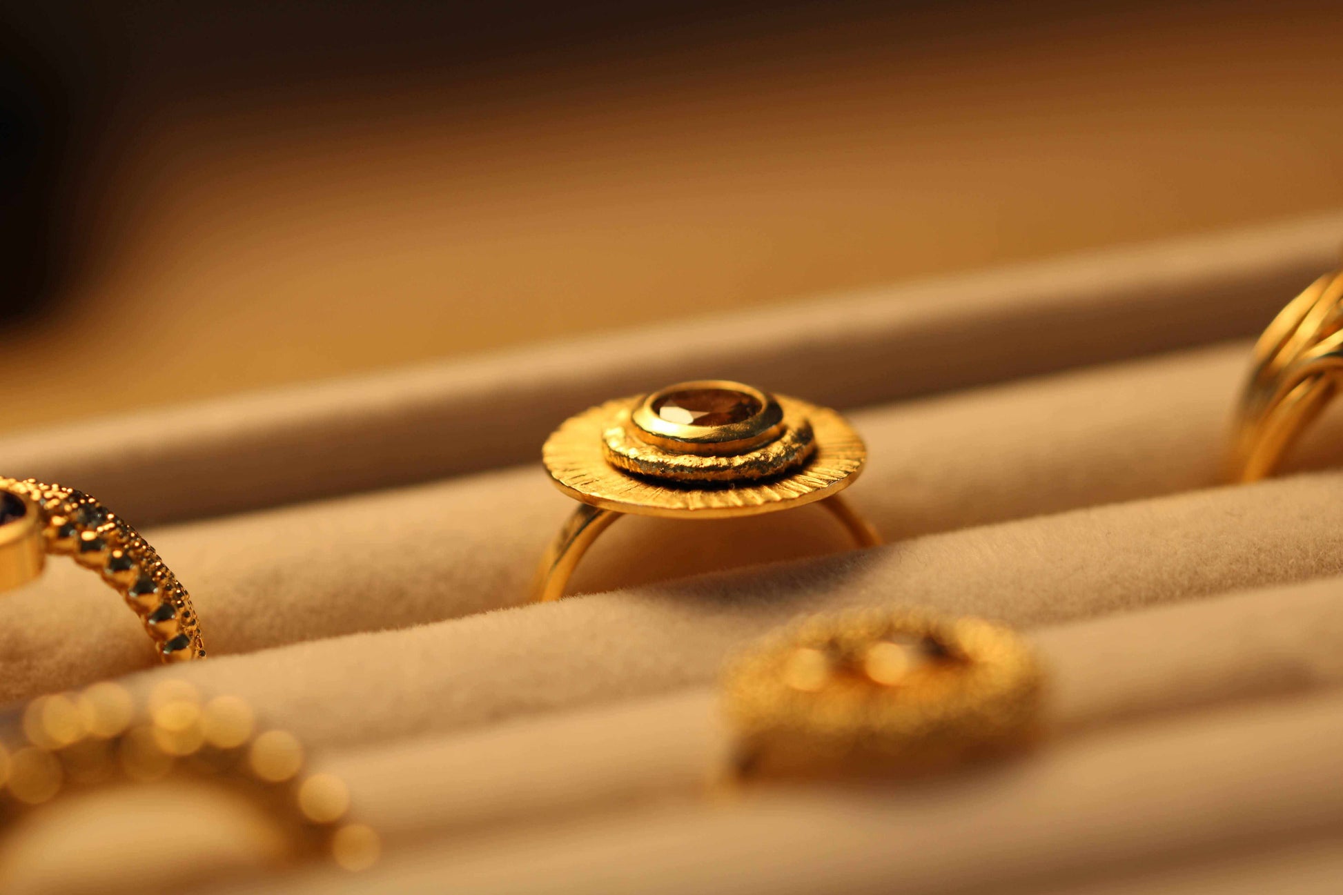 Fall Ring van Olivia Peeters Master Goldsmith: Gouden ring met een opvallend zonnestraalontwerp en een centraal geplaatste toermalijn, elegant gepresenteerd in een sieradendoos met een warme belichting die de details benadrukt.