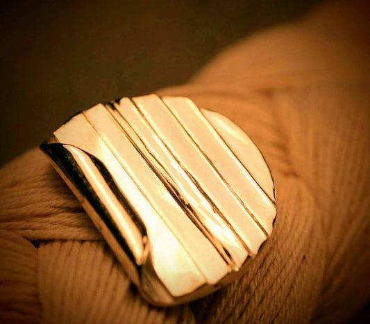 Folded Ridge Earrings van Olivia Peeters Master Goldsmith: Strakke gouden oorbellen met een geplooid, gelaagd en architecturaal ontwerp, gepresenteerd op een zachte textielachtergrond in warm licht.