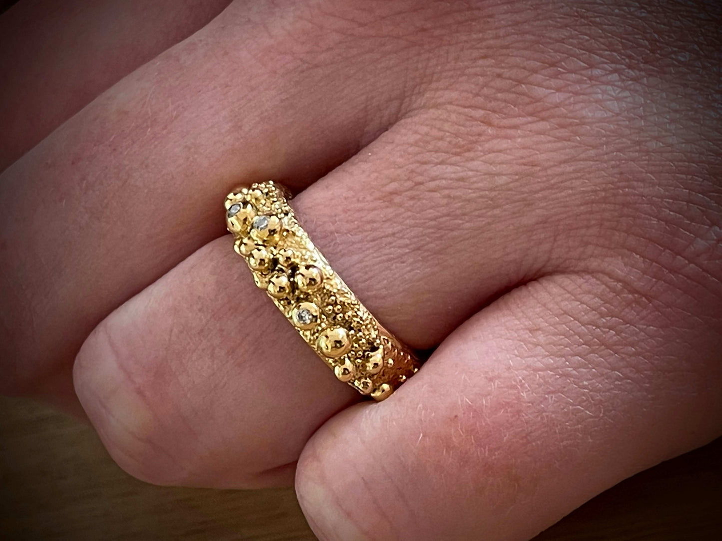 Love Bubbles ring van Olivia Peeters Master Goldsmith, een gouden ring met organische bolvormige details en subtiele diamantaccenten, gedragen op een hand en gefotografeerd in natuurlijk licht voor een warme en elegante uitstraling.
