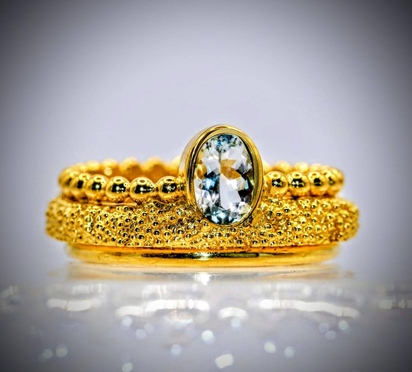 Stellwagen ring van Olivia Peeters Master Goldsmith, bestaande uit een gelaagd ontwerp met fijne gouden bolletjes en een opvallende ovale, transparante edelsteen als middelpunt. De ring straalt elegantie en verfijning uit.