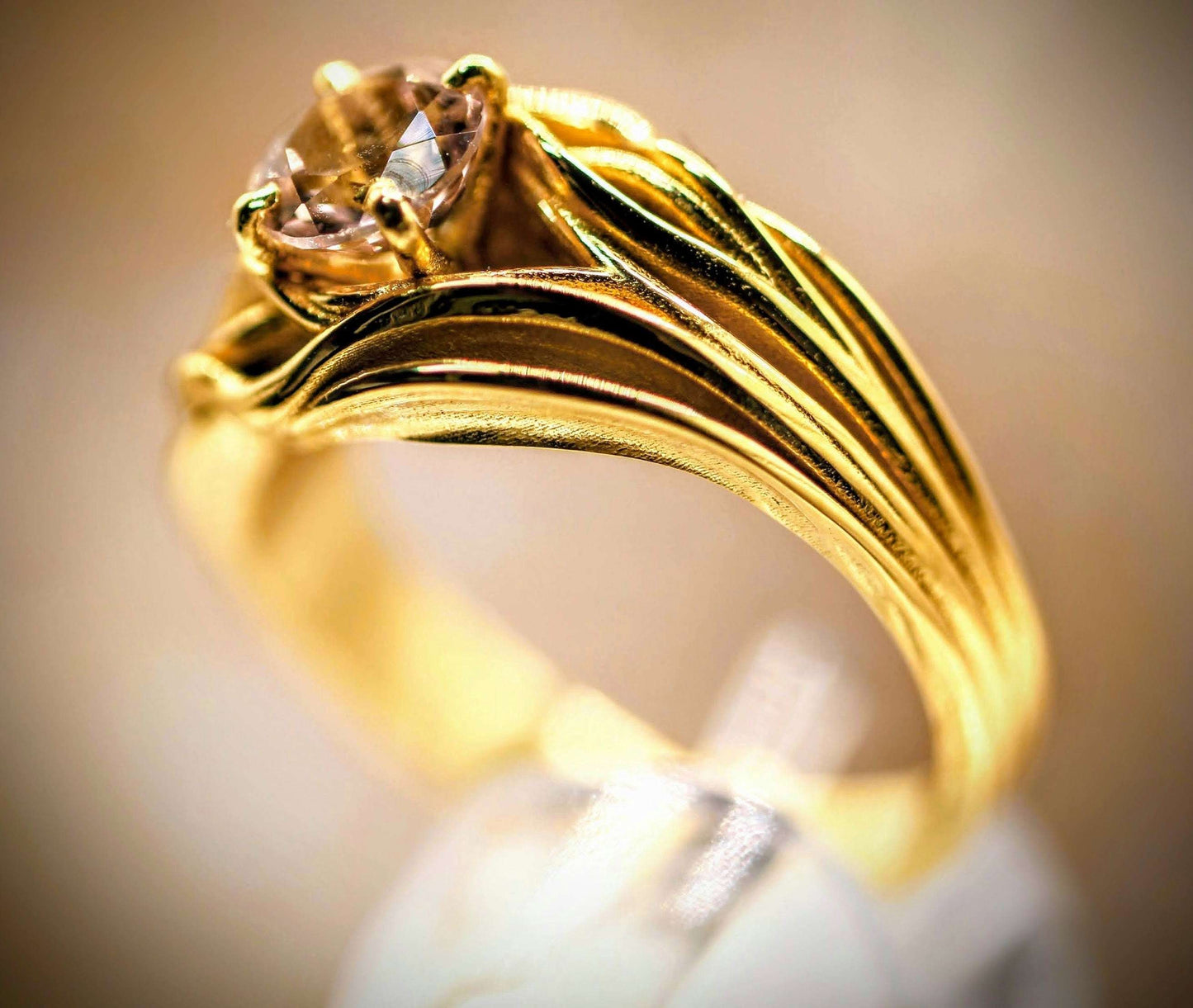 Sudden Wave Ring van Olivia Peeters Master Goldsmith, een verfijnde gouden ring met golvende lijnen die vloeiend naar een schitterende gefacetteerde steen leiden, geplaatst in een elegante zetting. Het organische ontwerp vangt beweging en dynamiek in een sierlijk juweel.