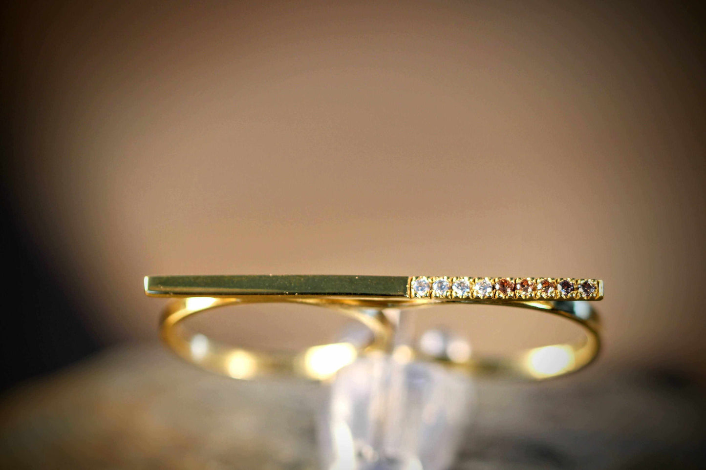 Morning Horizon van Olivia Peeters Master Goldsmith: Gouden ring met een slank en eigentijds ontwerp, voorzien van een rechte balk en een rij sprankelende diamanten, elegant gepresenteerd tegen een neutrale achtergrond.